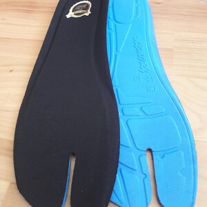 May include: Two split-toe shoe insoles. One insole is black with a gold emblem, the other is blue with the text "MEMORY" and size markings. The insoles are designed to fit shoes with a split toe.