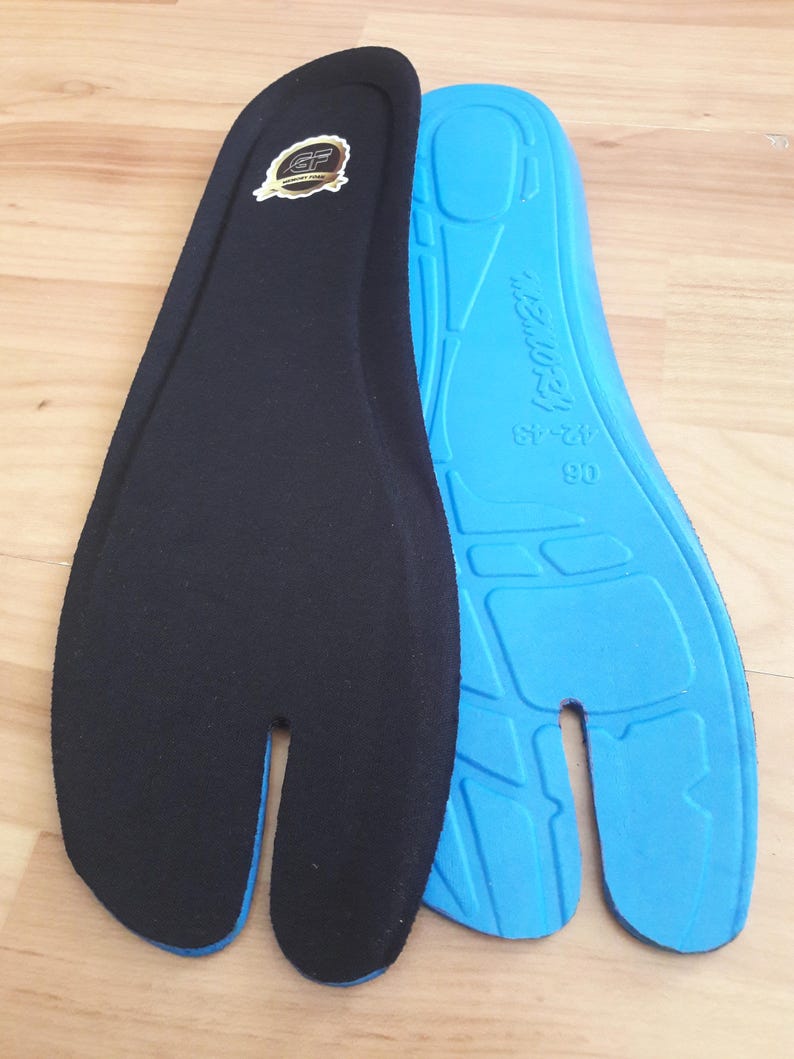 May include: Two split-toe shoe insoles. One insole is black with a gold emblem, the other is blue with the text "MEMORY" and size markings. The insoles are designed to fit shoes with a split toe.