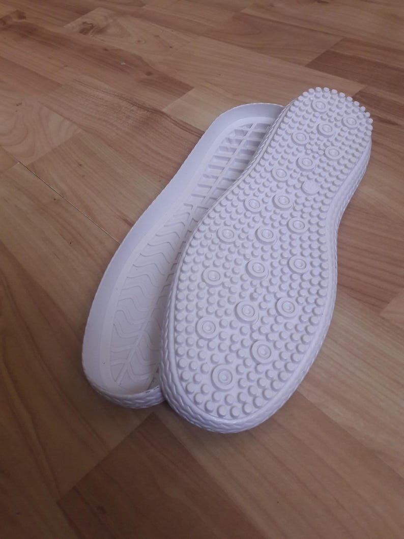 Op de afbeelding: Twee witte rubberen zool met een textuurpatroon. E&eacute;n zool heeft een golvend patroon en de andere heeft een patroon van kleine cirkels.