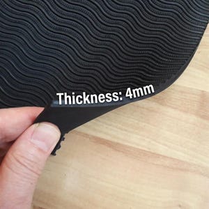 May include: A black rubber mat featuring a wavy, textured surface pattern. The material is flexible and has a clearly visible edge showing a thickness of 4mm, as indicated by the white text printed directly onto the mat's surface.