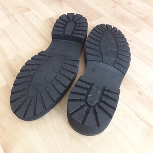 K&ouml;nnte beinhalten: Ein Paar schwarze, klobige Schuhsohlen mit tiefen Profilmustern. Die Sohlen bestehen aus einem strapazierf&auml;higen Material und sind f&uuml;r Traktion ausgelegt. Die Stiefel sind wahrscheinlich f&uuml;r den Au&szlig;enbereich gedacht.