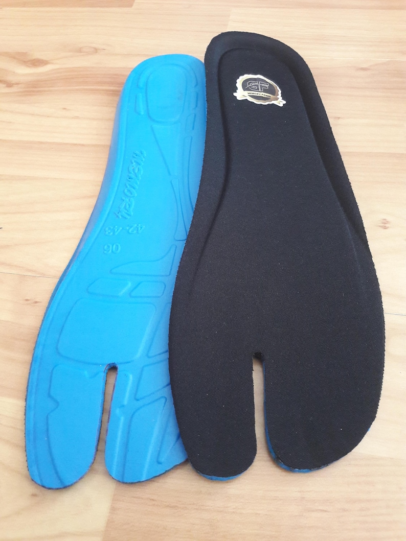 May include: Two split-toe insoles. One is bright blue with text and size markings, the other is black with a gold emblem. The insoles are designed to fit shoes with a split toe design.