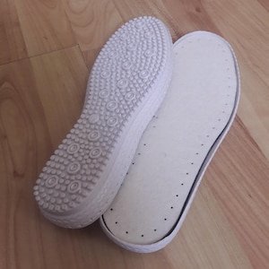 May include: Two white shoe insoles, one with a textured surface and the other with a smooth surface.