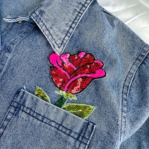 May include: A denim jacket with a red and pink sequined rose patch sewn onto the pocket.