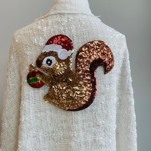 May include: White sequined jacket with a gold and red sequined squirrel wearing a Santa hat holding a Christmas ornament.