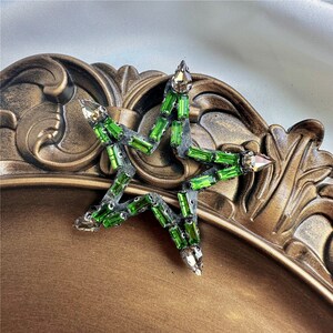 Peut inclure: Une &eacute;toile verte en forme d'&eacute;toile avec des strass. L'&eacute;toile est faite de tissu et a un dos en velours vert fonc&eacute;.