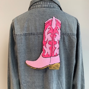 May include: A denim jacket with a pink sequined cowboy boot patch on the back.