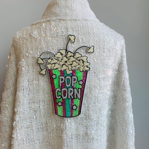 Popcorn Delight: parche termoadhesivo con forma de cubo de palomitas de maíz con lentejuelas en rayas rosas y verdes con letra de palomitas de maíz bordada