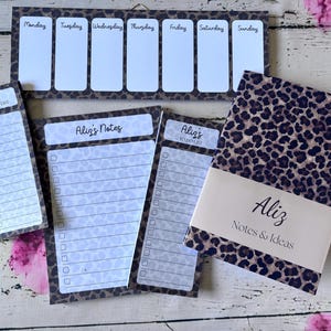 May include: A stationery set featuring a leopard print pattern, including a weekly planner with days of the week, a shopping list labelled Aliz's Shopping List, a notes pad labelled Aliz's Notes, a to-do list, and a notebook labelled Aliz Notes & Ideas.