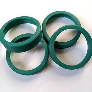 May include: Four green rubber rings of different sizes stacked on top of each other.