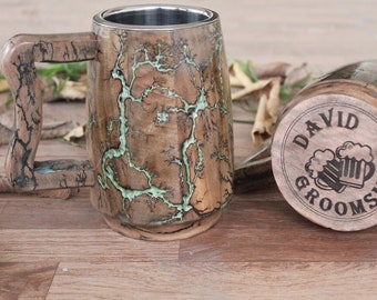 May include: Wooden beer mug with a stainless steel interior. The mug features a unique wood grain pattern with green accents. The bottom of the mug has the text "DAVID GROOMSMAN" and two beer mugs.