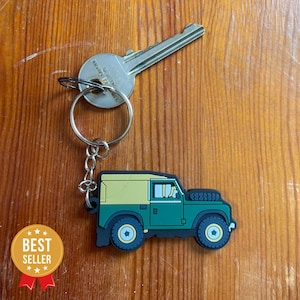 Puede incluir: Un llavero Land Rover verde y amarillo con una llave plateada adjunta. El llavero está hecho de goma y tiene un diseño detallado.
