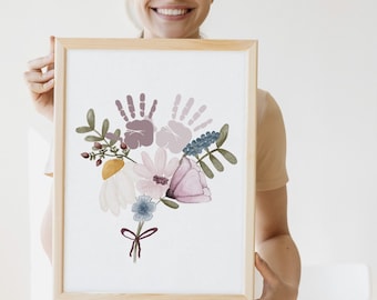 May include: A framed print with a watercolor painting of a bouquet of flowers. The flowers are in shades of pink, purple, and white. Two handprints are incorporated into the design, forming the center of the bouquet.