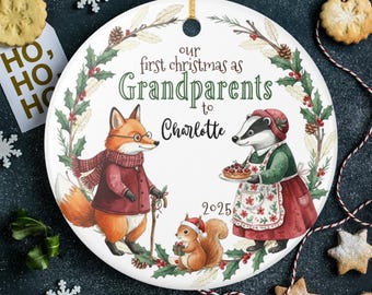 May include: A round Christmas ornament with a festive design. It features a fox and a badger dressed in winter attire, with a squirrel holding a gift. Text reads "Our first Christmas as Grandparents to Charlotte 2025."