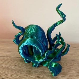 May include: A 3D printed octopus figurine with a blue and green iridescent finish. The octopus has eight tentacles and is curled up in a defensive position.