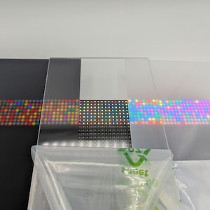 Pode incluir: Uma cole&ccedil;&atilde;o de pain&eacute;is transparentes e opacos, cada um exibindo uma grade de luzes LED coloridas. Os pain&eacute;is variam em cor, incluindo preto, transparente e fosco, com as luzes emitindo um espectro de tons. Um saco pl&aacute;stico est&aacute; em primeiro plano.