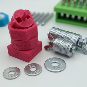 May include: A set of four pink plastic 3D printed parts stacked on top of each other. The top part has a small gear and the text "PULSE" printed on it. The second part has the text "PULSE CHAIN" printed on it. The third part has the text "PULSE CHAIN" printed on it. The bottom part has the text "PULSE CHAIN" printed on it. There are also two silver metal washers with a nut on each side.