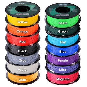 Pode incluir: Uma pilha de bobinas de filamento para impressora 3D coloridas. As cores incluem amarelo, laranja, vermelho, preto, cinza, branco e dourado &agrave; esquerda. Verde, azul celeste, azul, roxo, lil&aacute;s e magenta &agrave; direita. Cada bobina &eacute; rotulada com sua cor.