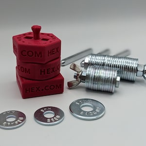 May include: A set of three red plastic hexagonal blocks stacked on top of each other. The blocks have the text "HEX.COM" and "COM HEX" printed on them. The set also includes two silver metal hex wrenches and two silver metal washers.
