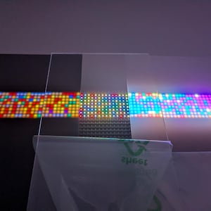 Pode incluir: Imagem abstrata com pain&eacute;is de LED iluminados. Os pain&eacute;is exibem padr&otilde;es vibrantes de luzes vermelhas, amarelas, verdes, azuis e roxas. As luzes s&atilde;o dispostas em uma forma&ccedil;&atilde;o de grade, criando uma exibi&ccedil;&atilde;o din&acirc;mica e colorida.