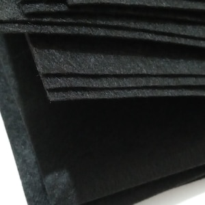 May include: A stack of black felt sheets. The felt is smooth and has a slight sheen.