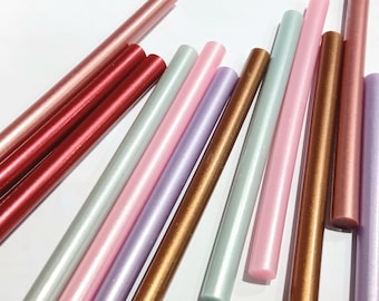 May include: An assortment of colorful sealing wax sticks in various shades of red, pink, silver, gold, and purple. The sticks are cylindrical and have a glossy finish, perfect for adding a decorative touch to crafts and stationery.