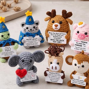 Può includere: Una collezione di sette piccole figure di animali all'uncinetto tra cui una tartaruga, un gatto, un cervo, un maiale, un elefante, un cavallo e una scimmia. Ogni figura tiene un cartoncino bianco con testo stampato e colori distinti.