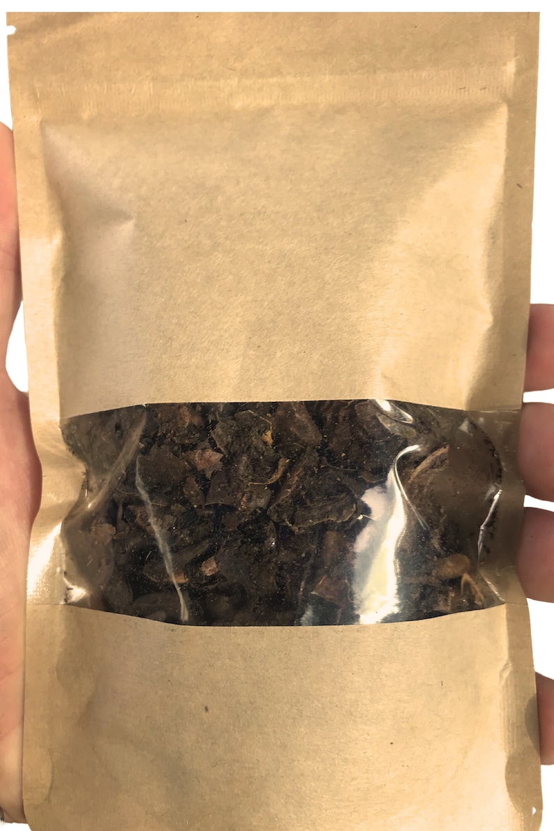 以下が含まれることがあります： 中央に透明なプラスチック窓が付いた長方形の茶色の紙袋。袋の中には、不規則な形の暗褐色の乾燥した有機物が詰められており、透明な窓からその質感のある脆そうな様子が見えています。