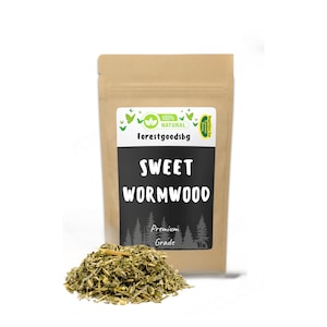 May include: A brown paper pouch containing dried sweet wormwood herbs. The label features the text Forestgoodsbg, 100% NATURAL, SWEET WORMWOOD, and Premium Grade, with green butterfly and pine tree graphics. A pile of dried green herbs sits in front.