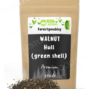 以下が含まれることがあります： Forestgoodsbg、100% Natural、Walnut Hull (green shell)、Premium gradeと書かれた白と黒のラベルが付いた、クルミの殻（緑色の殻）が入った茶色の紙袋。手前には、濃い茶色の粒状のクルミの殻が山積みになっています。