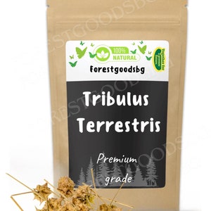 Op de afbeelding: Een bruine papieren zak met een wit label waarop "100% NATUURLIJK" en "Forestgoodsbg" staat. Het label heeft ook een zwarte achtergrond met witte tekst waarop "Tribulus Terrestris" en "Premium kwaliteit" staat. Er zijn vlinders en een groen blad op het label. De zak is gevuld met gedroogde Tribulus Terrestris.