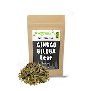 Op de afbeelding: Een bruine papieren zak met een label waarop staat "100% NATUURLIJK forestgoodsbg GINKGO BILOBA Leaf Premium Grade". De zak bevat gedroogde groene ginkgo biloba bladeren.