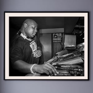 Könnte beinhalten: Schwarzweißfoto eines Mannes mit Kopfhörern und schwarzem Hemd, der Musik an einem DJ-Mixer mischt.