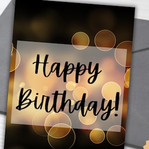May include: Printable birthday card with a black background and gold bokeh lights. The card reads "Happy Birthday!" in black text.