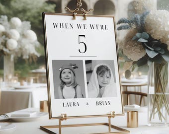May include: A gold-colored metal stand with a white card featuring a black and white photo of a couple as children. The card reads "When we were 5" and includes the names "Laura & Brian".
