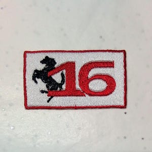 May include: Rectangular embroidered patch with a red border. The patch features the number '16' in red, and a black prancing horse logo on a white background.
