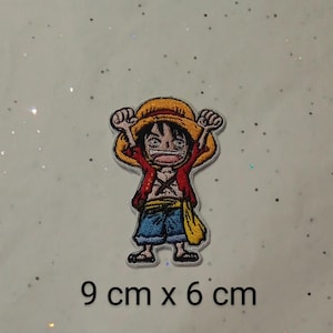 May include: Embroidered patch featuring a cartoon character with a straw hat, red jacket, and blue pants. The patch measures 3.5 inches by 2.4 inches and has the text "9 cm x 6 cm".