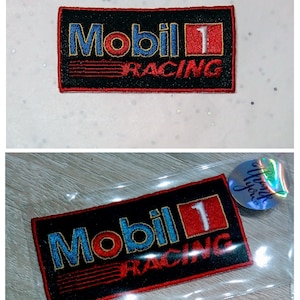 Op de afbeelding: Geborduurde Mobil 1 Racing patch met een zwarte achtergrond. De patch heeft het Mobil 1 logo in blauw en rood, met het nummer 1 in een rode vierkant. Het woord "RACING" staat in rood onder het logo.