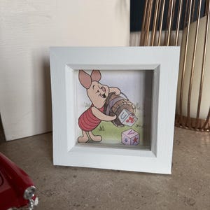 Puede incluir: Un marco blanco con una imagen de un cerdo de dibujos animados sosteniendo una cesta de bloques. Los bloques están etiquetados con las letras "U" y "V".