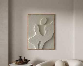 May include: A white armchair with rounded edges and a single pillow sits in a room with a beige wall and a framed abstract art print. A small wooden table with a white marble top sits in the foreground.