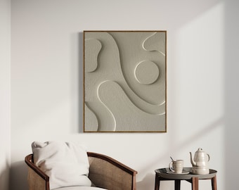 May include: A framed abstract wall art piece with a textured, light beige surface and a dark brown wooden frame. The artwork features flowing, organic shapes. A white armchair and a small side table with a teapot and cup are in the foreground.
