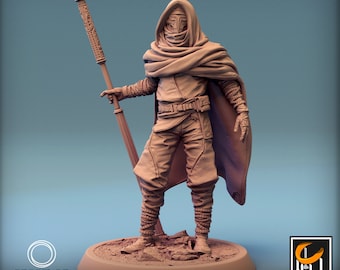 Puede incluir: Una figura en miniatura impresa en 3D de una persona que lleva una capa con capucha y una máscara, sosteniendo un bastón. La figura está de pie sobre una base circular con una superficie texturizada. La figura está pintada en un color marrón claro.