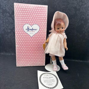 Puede incluir: Muñeca vintage Effanbee Patsy Joan con vestido, gorro y zapatos rosas, con calcetines blancos. La muñeca se exhibe con su caja original, con un patrón de corazones y un certificado de autenticidad.