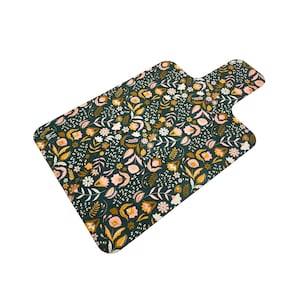 May include: A dark green cutting board with a floral pattern in shades of pink and gold. The board has a handle on one side.