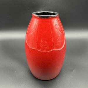 Peut inclure: Un vase en céramique brillant en forme de tonneau avec une finition extérieure rouge vif et unie. Le vase présente une ouverture étroite et arrondie au sommet avec un bord noir lisse et distinct qui contraste avec le corps rouge vif.