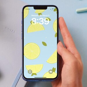 May include: A blue iPhone with a lemon-themed wallpaper. The time is 8:39 and the date is Wednesday, March 5.