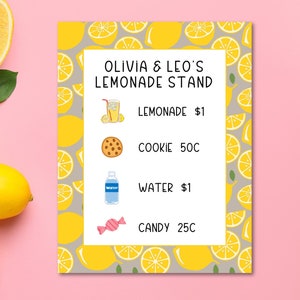 May include: A lemonade stand sign with a yellow and gray lemon pattern. The sign reads "Olivia & Leo's Lemonade Stand" and lists the prices for lemonade, cookies, water, and candy.