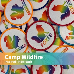 May include: A collection of circular embroidered patches featuring rainbow-coloured animal silhouettes including squirrels, foxes, and hawks. Each white patch has a coloured border and text identifying the animal, such as SQUIRRELS, FOXES, or HAWKS.