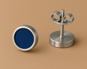 May include: A pair of stud earrings with a brushed metal finish. Each earring features a circular design with a deep blue center. The earring posts and backs are also visible, showcasing the complete set.