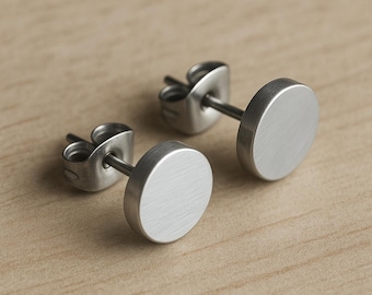 May include: A pair of silver stud earrings with a circular design. The earrings have a brushed finish.